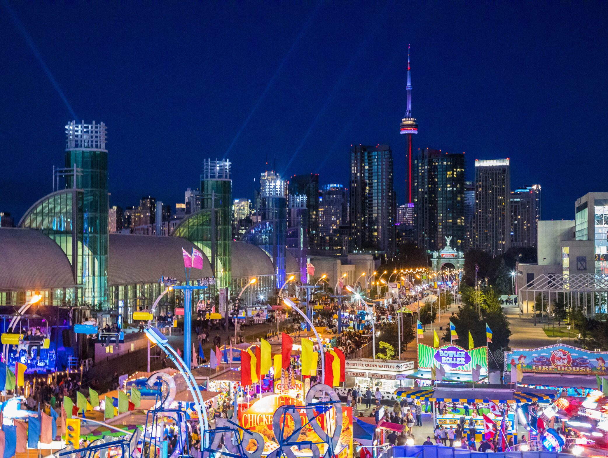 Aerial view of the Toronto skyline at night. Image of the CNE Midway, Enercare Centre, and CN Tower in the background.