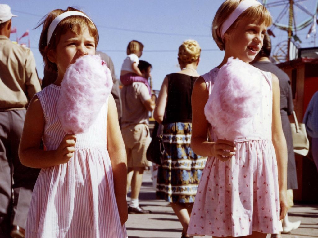 Two young girls at the fair with cotton candy.